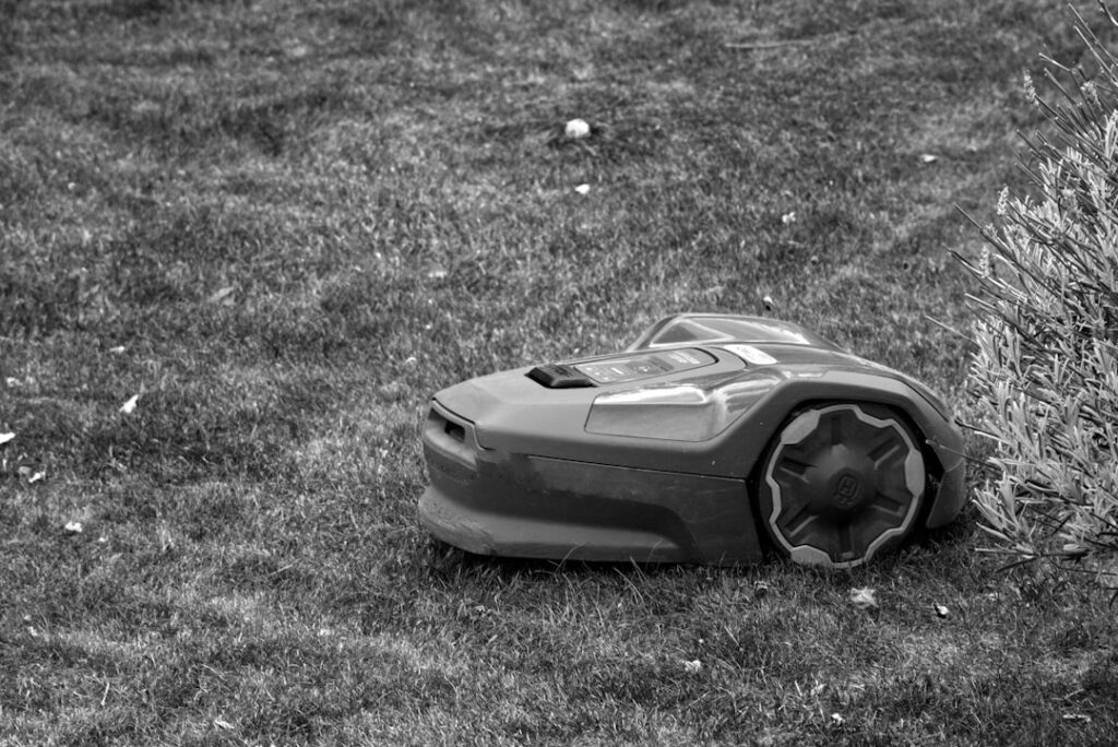 Familie mit Kindern beobachtet sicheren Rasenmäher Roboter beim smarten Mähen im Garten